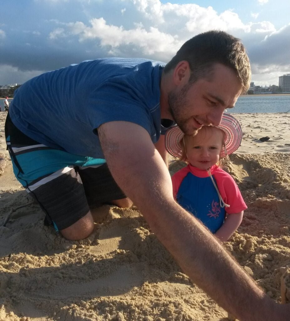 man and girl playing in sand