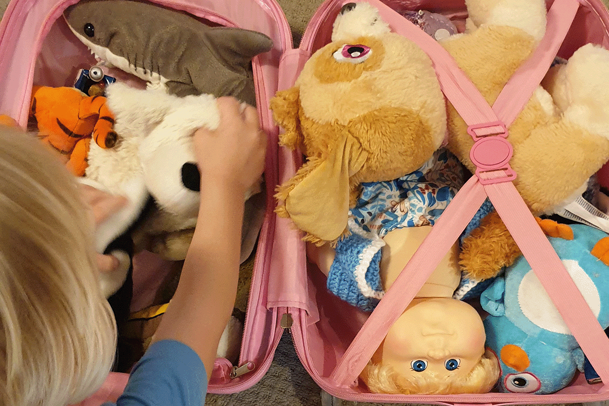 little child packing a small pink suitcase